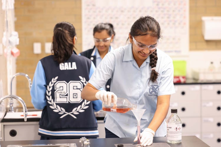 Three students performing experiments in a science lab