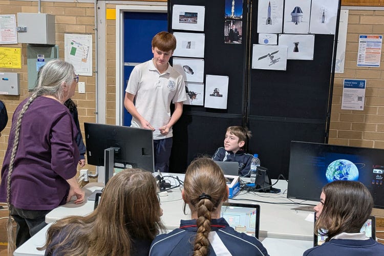 Two students presenting their Prosperitas project to a teacher and other students